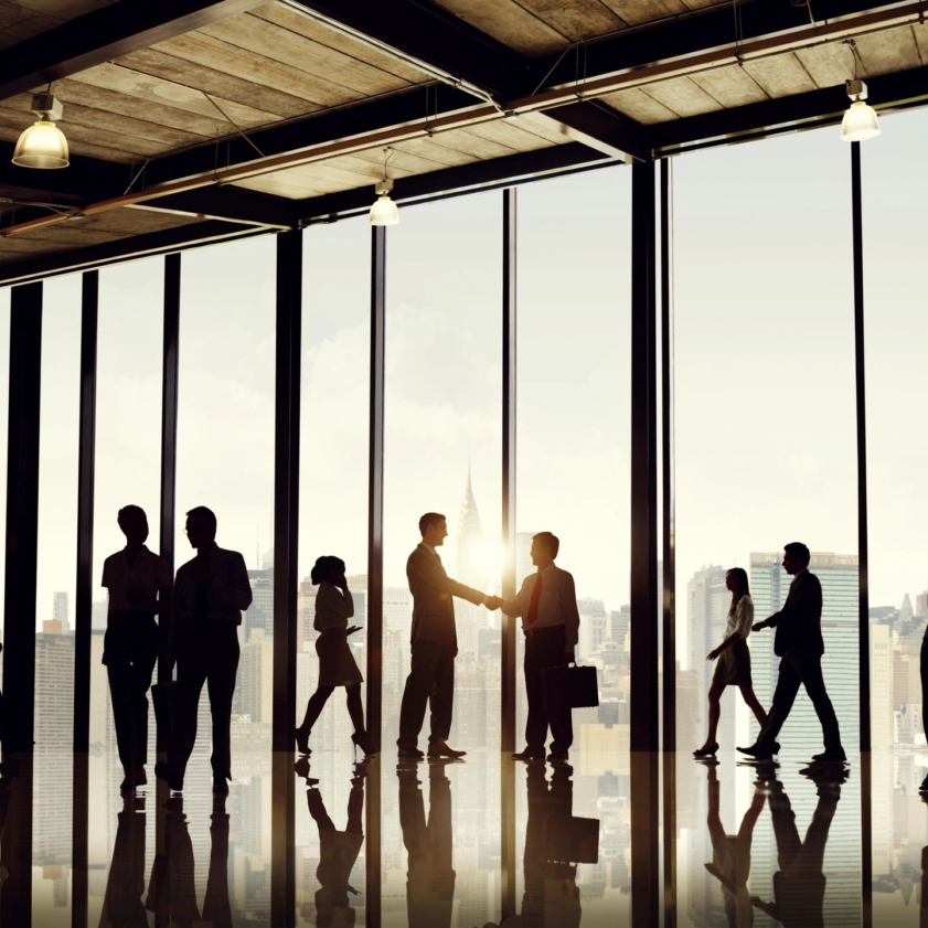 A group of people standing in front of large windows.